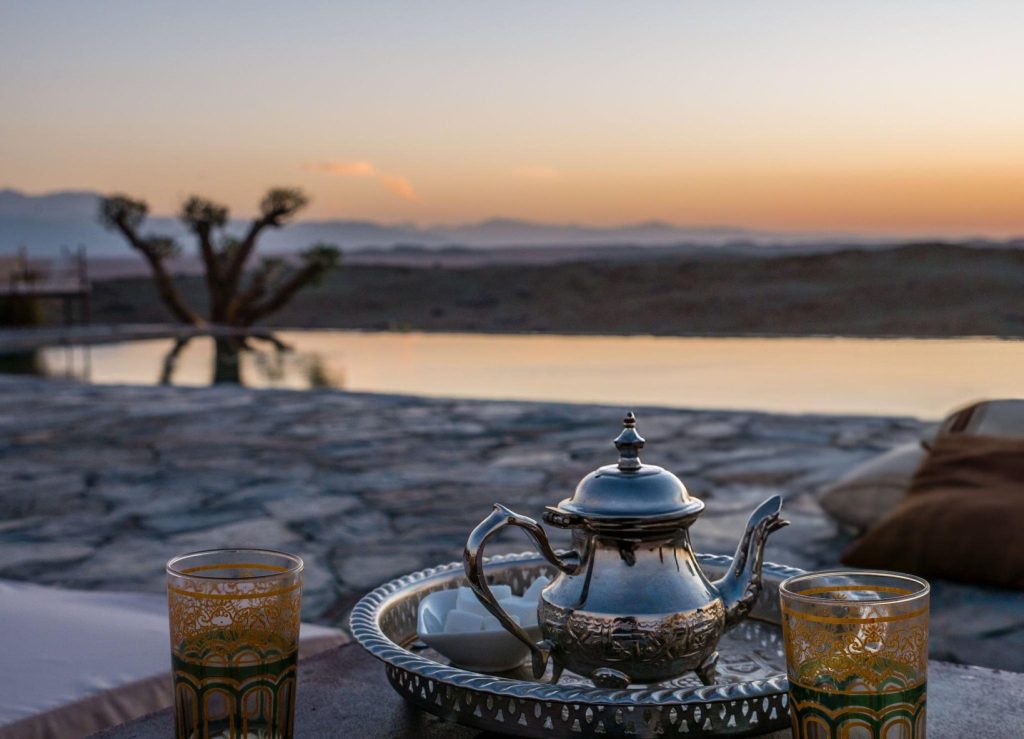 A selective focus closeup shot of a typical Moroccan mint tea set on the table in Agafay desert, Marrakech

